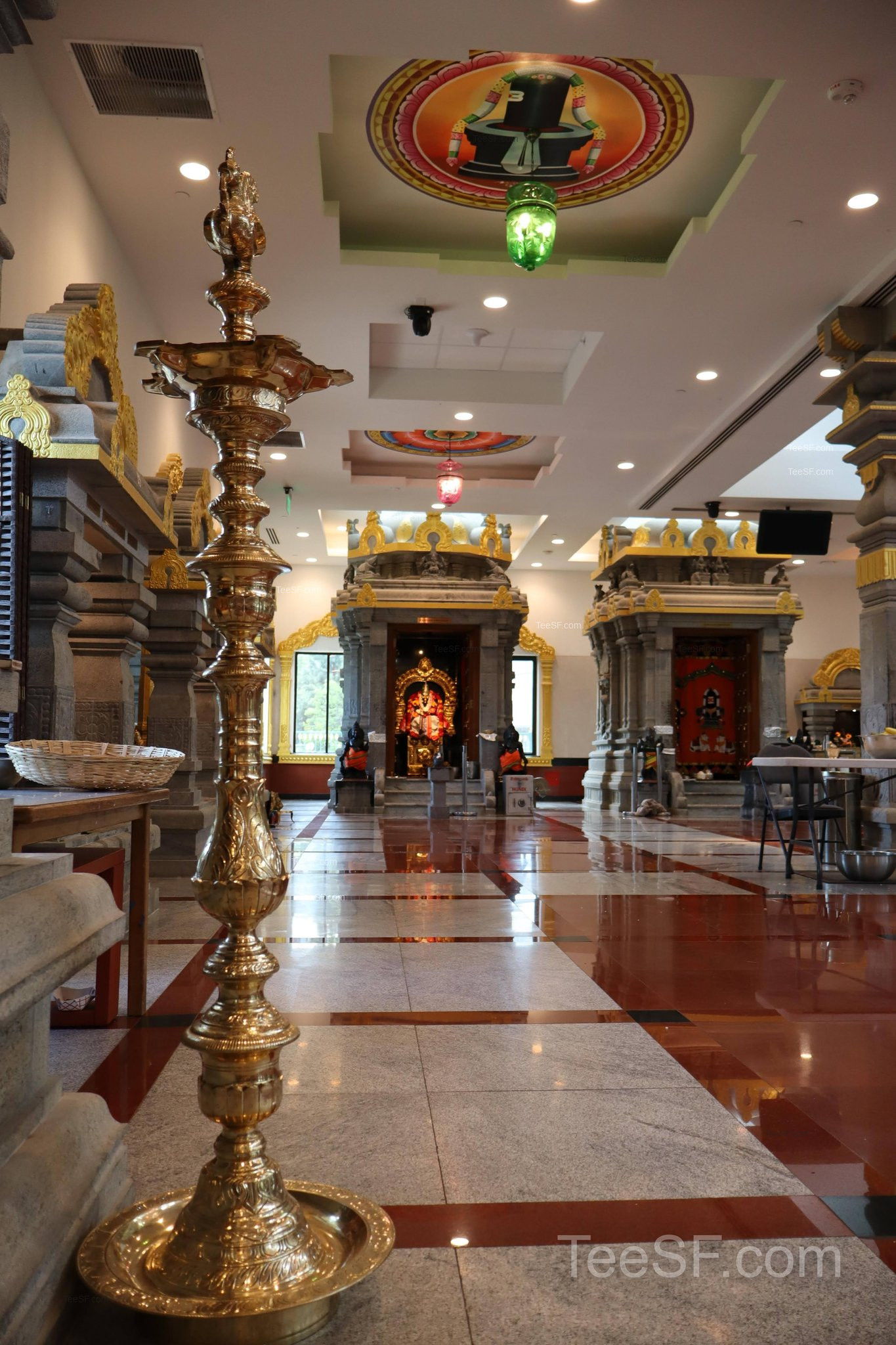 A quiet interior hallway with lamps and shrine details at Shiva Murugan Temple.